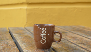Fotografi af et skåret kaffekrus på et træbord med regndråber